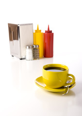 A cafe or coffee shop tabletop setup with a yellow cup