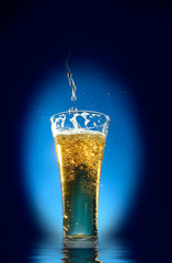 Glass of beer  close-up with froth over blue background