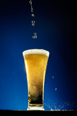 Glass of beer  close-up with froth over blue background