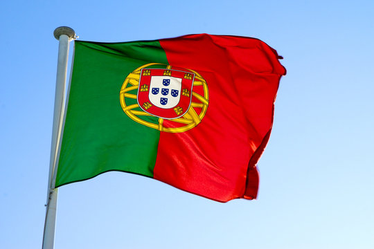 Portuguese national flag waving against a clear blue sky