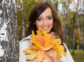 smiley woman with autumn leaves near the birch