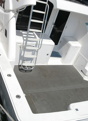 A close-up view of the rear deck of a sleek white yacht featuring a clean gray floor, built-in...