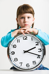 Cute little girl with big clock watching