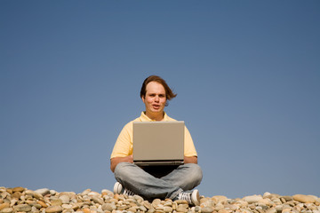 Naklejka na ściany i meble young casual man with laptop at the beach