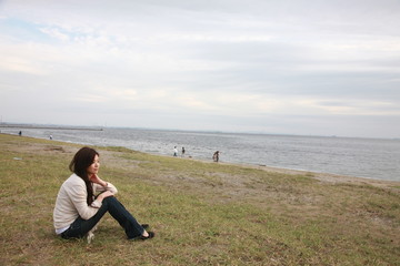 Fototapeta premium young woman sits down on a beach