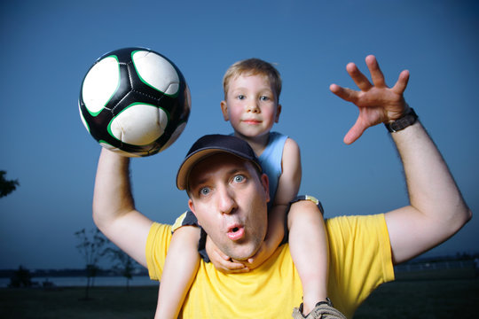 Dad And Son Playing Football Outdoors