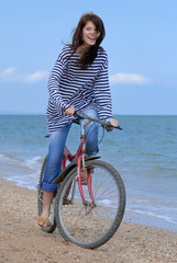 A Happy girl in a striped vest cycling on the sea background