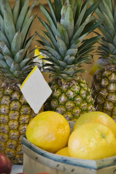 Pineapples standing tall graced by a basket of lemons.
