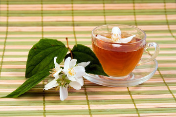 Transparent teacup with tea and flower