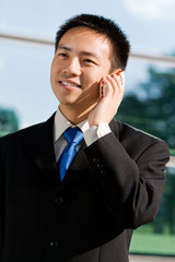 Good looking asian business man with mobile phone.