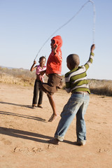 african children jumping rope in the sand,