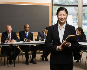 Asian businesswoman standing in front of co-workers
