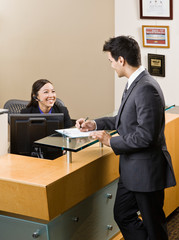 Fototapeta na wymiar Friendly receptionist greeting man at front desk
