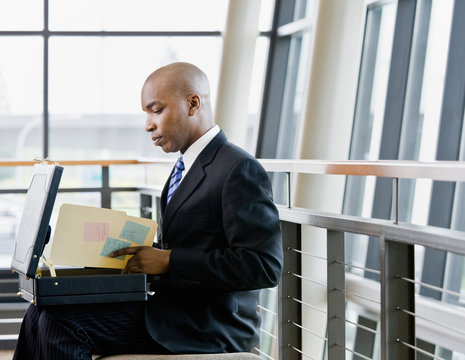 African businessman reviewing files in briefcase in office lobby