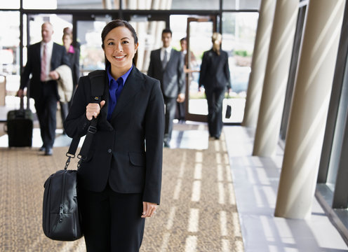 Happy businesswoman in full suit holding briefcase