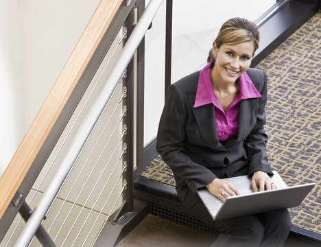 Businesswoman working on laptop on office stair landing