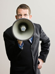 Angry businessman shouting instructions into megaphone