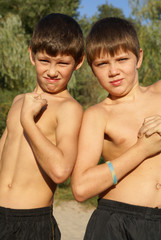 Two preteen boys showing big muscles outdoors