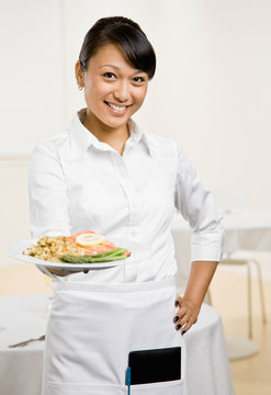 Waitress serving healthy dinner of salmon and asparagus
