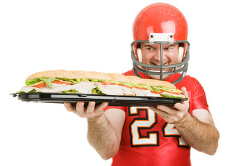 Football player hungrily looking at a giant sub sandwich.