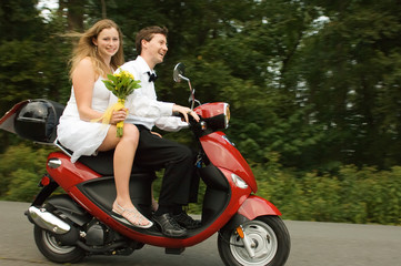 Obraz na płótnie Canvas Happy young married couple on a scooter
