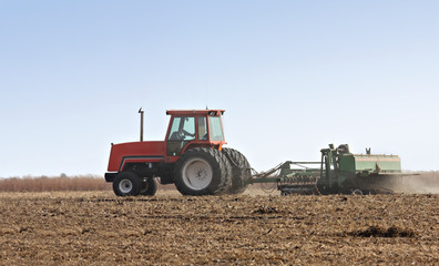 Obraz premium Farm tractor discing a field after harvest