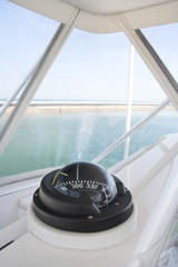 A close-up view of the cockpit of a modern yacht, featuring a polished chrome steering wheel,...