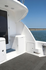 A close-up view of the rear deck of a sleek white yacht featuring a clean gray floor, built-in...