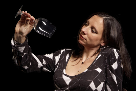 erwachsene Frau schaut ernst auf leeres Weinglas