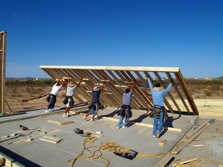 Construction workers lifting a wall frame into position.