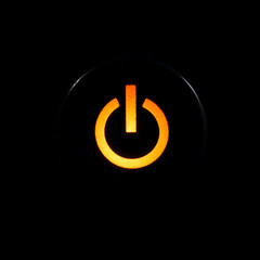 Amber glowing power button on black background