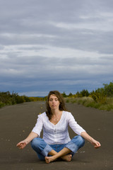 Fototapeta na wymiar Woman meditating in the middle of the road
