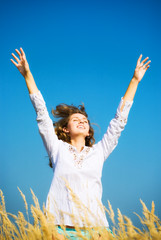 Young happy jumping woman. On blue sky background.