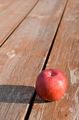 Freshly picked red apple on weathered picnic table