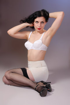 Retro pin-up girl in vintage bra, girdle & fishnet stockings
