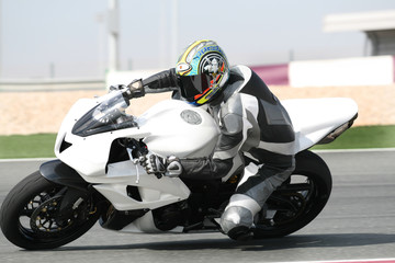 Motorbike accelerating on racetrack, leaning into sharp bend