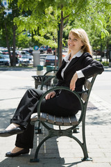 A caucasian businesswoman sitting on a bench outdoor