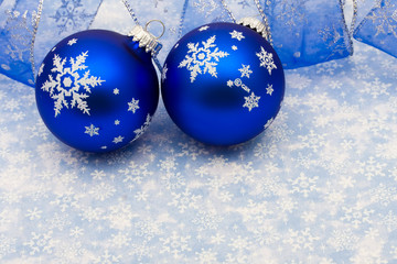 Blue glass ball and ribbon on blue snowflake background