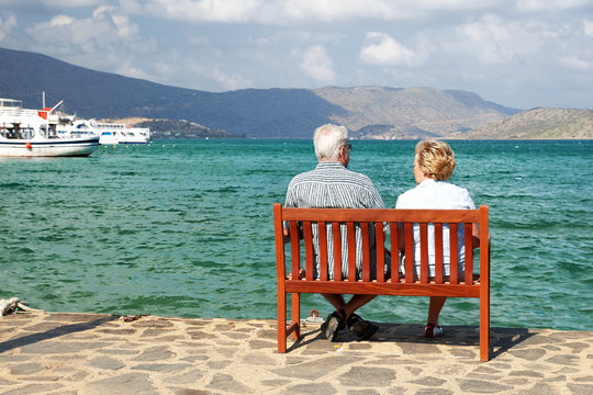 A man and a woman sitting on a bench and watching the sea - Powered by Adobe