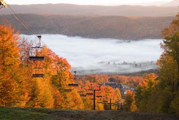 Chairlift on a fall mountain slope with morning mist - Powered by Adobe
