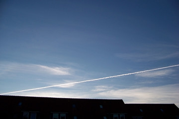 Fototapeta premium Trace from the plane in the evening sky over a house roof