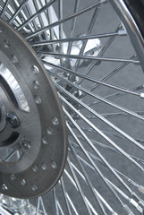 Detail of chrome motorbike wheel with lots of spokes.