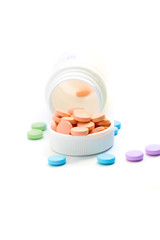 Color pills spilling from bottle on white