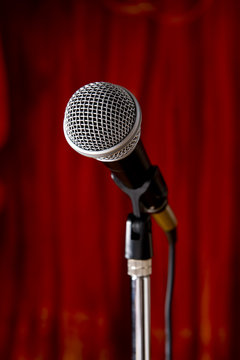 A microphone on a red curtain stage background