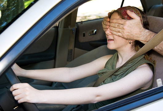 Teen girl gets the feel of the car  & someone covers her eyes.