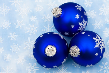 Blue glass Christmas balls on snowflake background