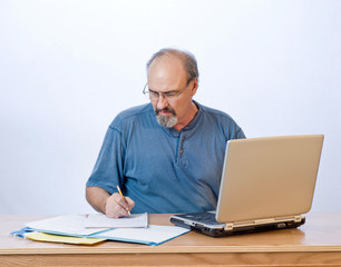 A businessman takes notes from the computer search results.