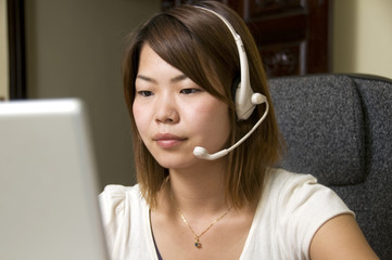 Attractive young Asian woman with headset and computer