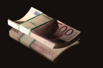 Bundle of euro bank notes lying on black background