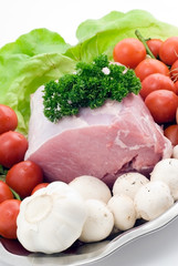 Raw pork on the plate with tomatoes,garlic and mushrooms